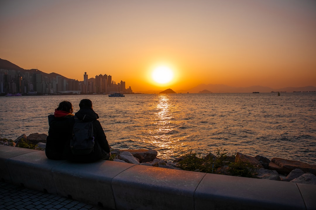 a-couple-of-people-sitting-on-top-of-a-stone-wall-diwrsswfjoy